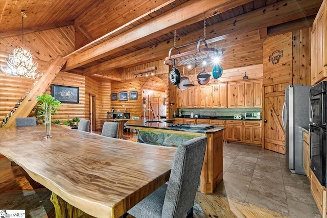 dining room with sink, rustic walls, beam ceiling, high vaulted ceiling, and wooden ceiling