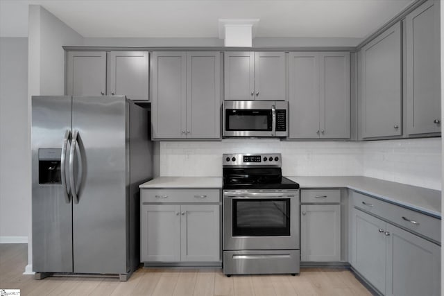 kitchen with decorative backsplash, gray cabinets, light hardwood / wood-style floors, and appliances with stainless steel finishes