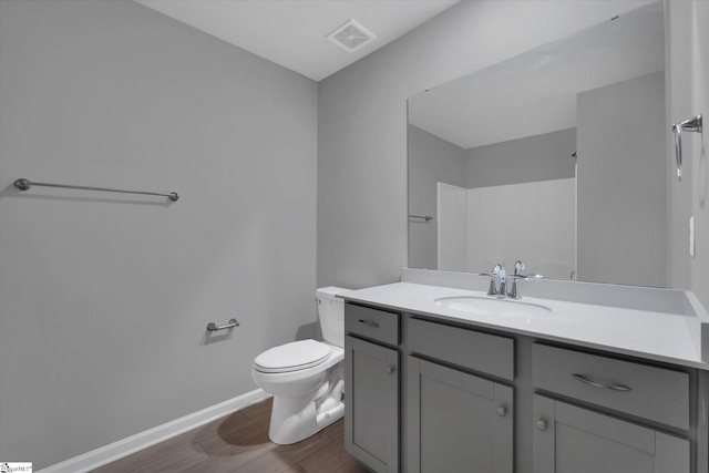 bathroom featuring hardwood / wood-style flooring, vanity, toilet, and walk in shower