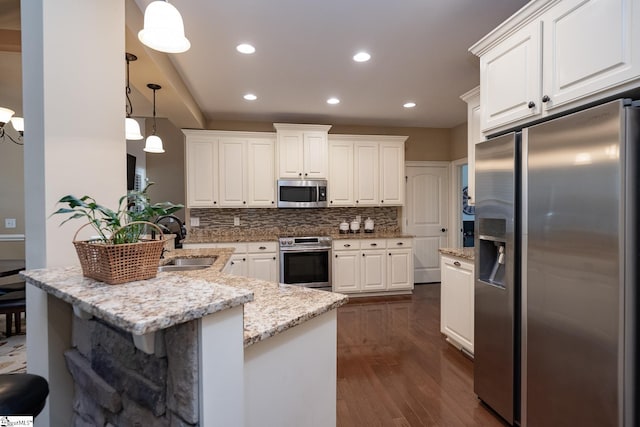 kitchen with appliances with stainless steel finishes, decorative light fixtures, tasteful backsplash, sink, and white cabinets