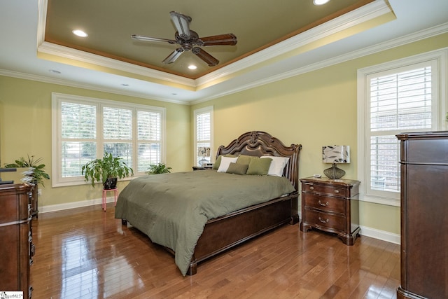 bedroom featuring hardwood / wood-style floors, ornamental molding, and a raised ceiling