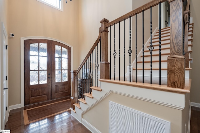 foyer entrance with a high ceiling, dark hardwood / wood-style flooring, and french doors