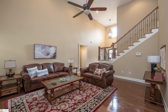 living room featuring dark hardwood / wood-style flooring, a towering ceiling, and ceiling fan