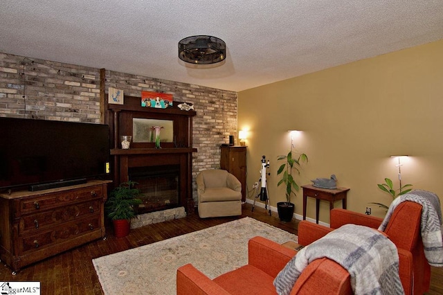 living room featuring a large fireplace, dark hardwood / wood-style flooring, and a textured ceiling