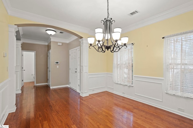 unfurnished dining area featuring dark wood-type flooring, crown molding, and decorative columns