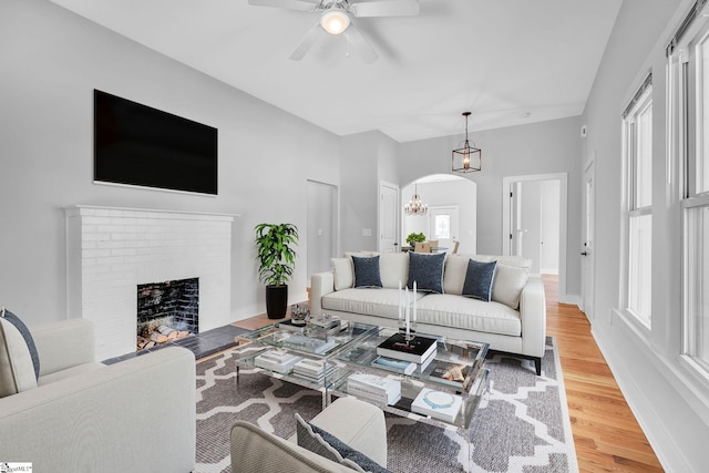 living room featuring hardwood / wood-style flooring, a fireplace, and ceiling fan with notable chandelier