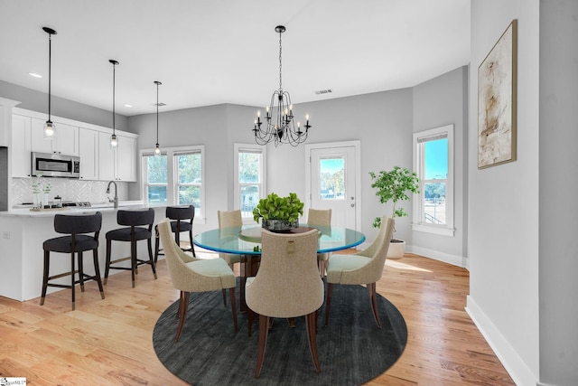 dining room featuring an inviting chandelier, sink, and light hardwood / wood-style floors