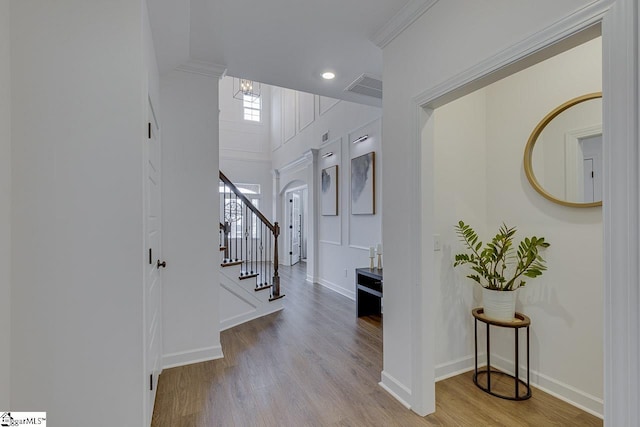 foyer featuring crown molding, light hardwood / wood-style floors, and ornate columns