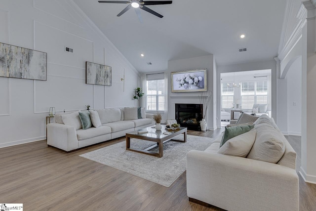 living room featuring hardwood / wood-style flooring, ceiling fan, crown molding, and high vaulted ceiling