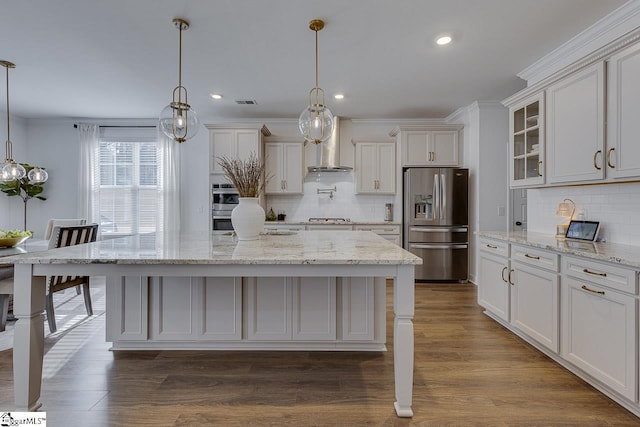 kitchen featuring a kitchen island with sink, hanging light fixtures, wall chimney range hood, and appliances with stainless steel finishes