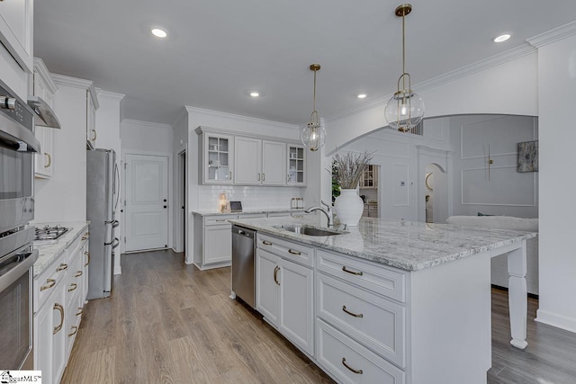 kitchen with pendant lighting, sink, appliances with stainless steel finishes, white cabinetry, and a center island with sink