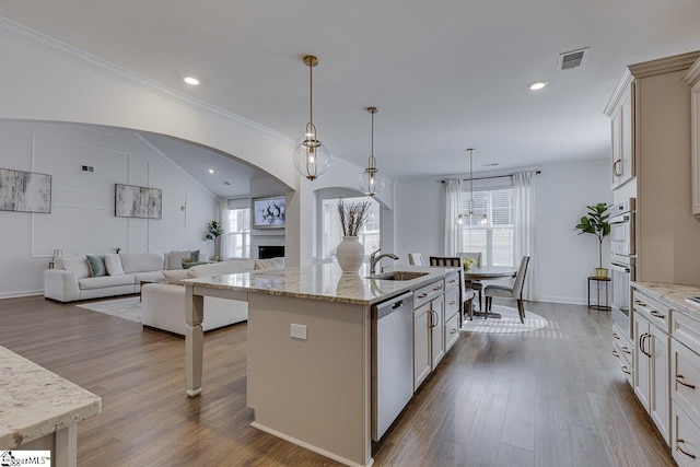 kitchen featuring appliances with stainless steel finishes, pendant lighting, an island with sink, sink, and hardwood / wood-style flooring