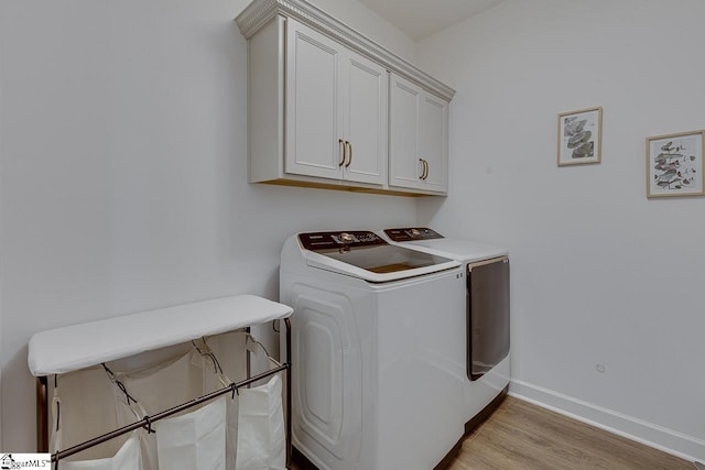 clothes washing area featuring cabinets, light hardwood / wood-style flooring, and washer and dryer