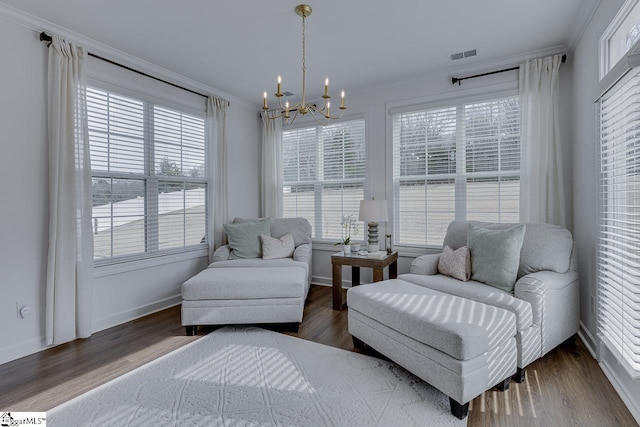 living area featuring dark hardwood / wood-style flooring, ornamental molding, and a chandelier