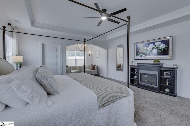 carpeted bedroom featuring crown molding, a raised ceiling, and ceiling fan with notable chandelier