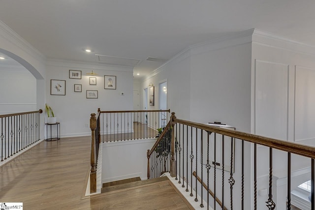 staircase with wood-type flooring and ornamental molding