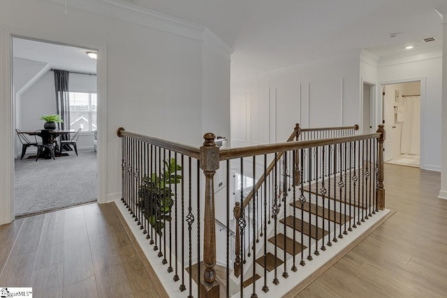 corridor with ornamental molding and light hardwood / wood-style floors