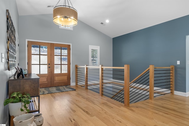 entrance foyer featuring hardwood / wood-style flooring, high vaulted ceiling, and french doors