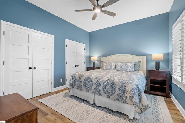 bedroom featuring hardwood / wood-style flooring, multiple closets, and ceiling fan