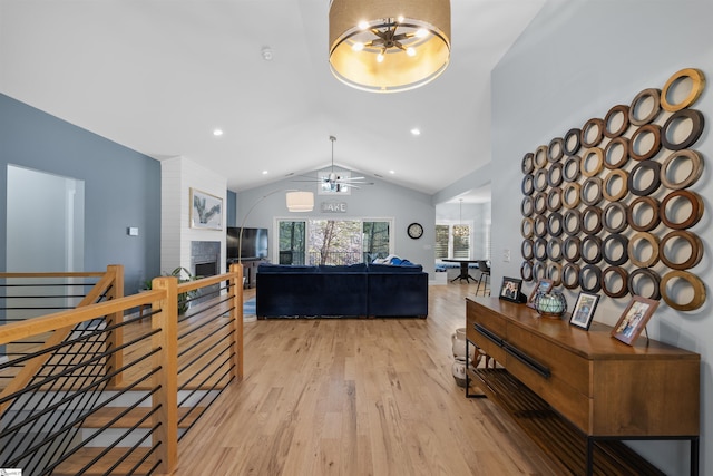 living room with ceiling fan with notable chandelier, vaulted ceiling, and light hardwood / wood-style floors