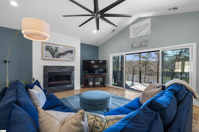 living room featuring hardwood / wood-style floors, plenty of natural light, a fireplace, and high vaulted ceiling