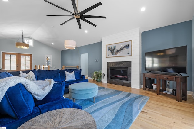 living room with french doors, vaulted ceiling, light hardwood / wood-style flooring, ceiling fan, and a fireplace