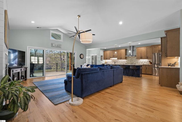 living room featuring ceiling fan, high vaulted ceiling, sink, and light hardwood / wood-style floors