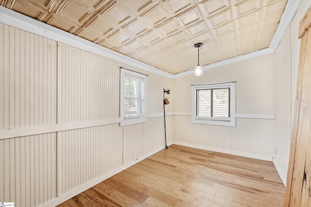 empty room featuring hardwood / wood-style floors, ornamental molding, and a healthy amount of sunlight