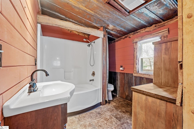 full bathroom with vanity, wooden walls, shower / tub combination, and toilet