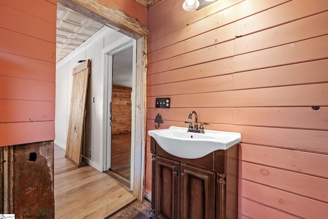 bathroom featuring vanity, hardwood / wood-style floors, and wood walls