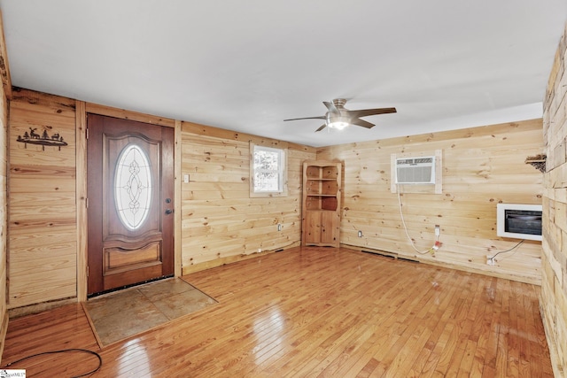 foyer with hardwood / wood-style flooring, ceiling fan, wooden walls, a wall unit AC, and heating unit