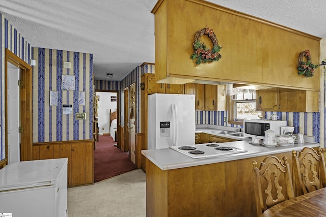 kitchen featuring sink, white appliances, kitchen peninsula, and a textured ceiling