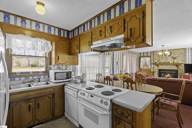 kitchen with white appliances, decorative light fixtures, sink, and a textured ceiling