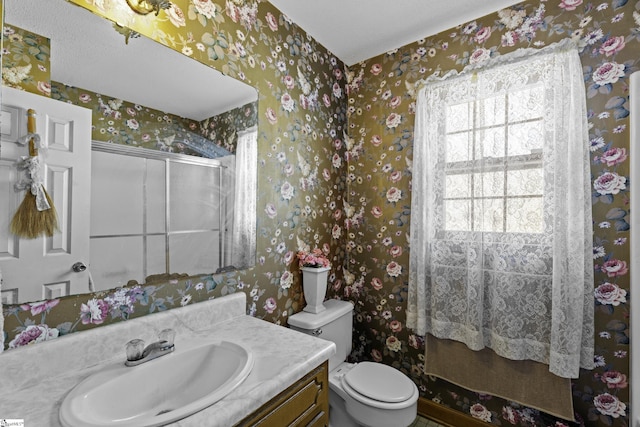 bathroom with vanity, a shower with shower door, and toilet