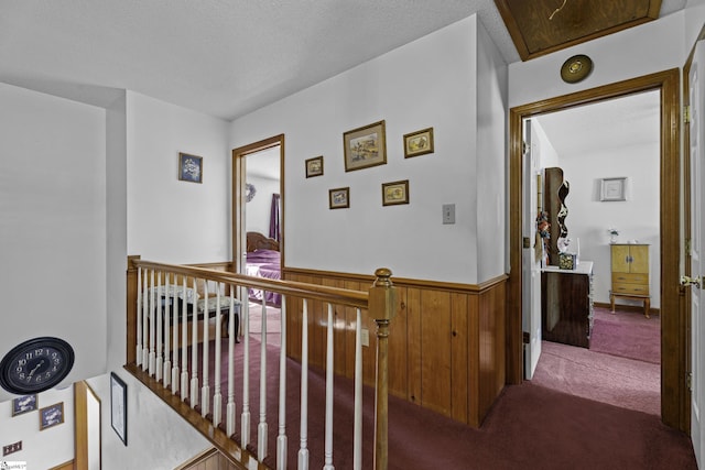 corridor with wooden walls, carpet flooring, and a textured ceiling