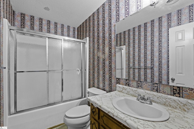 full bathroom with vanity, combined bath / shower with glass door, toilet, and a textured ceiling