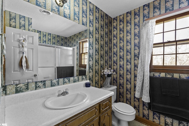 bathroom featuring vanity, toilet, a textured ceiling, and walk in shower