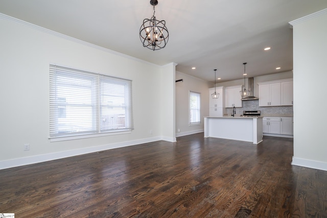 unfurnished living room with dark wood-type flooring, sink, crown molding, and an inviting chandelier