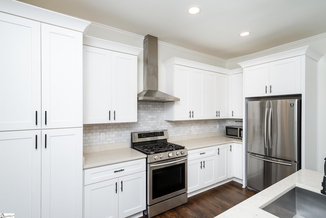 kitchen featuring tasteful backsplash, wall chimney range hood, stainless steel appliances, and white cabinets