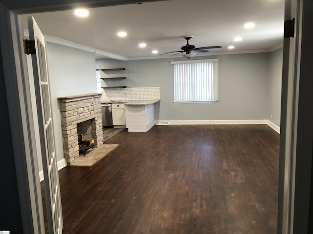 unfurnished living room with ornamental molding, a stone fireplace, ceiling fan, and dark hardwood / wood-style flooring