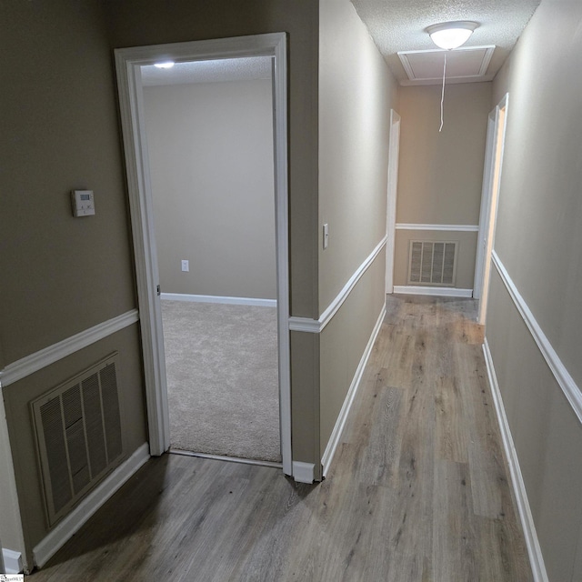 hallway with light hardwood / wood-style floors and a textured ceiling