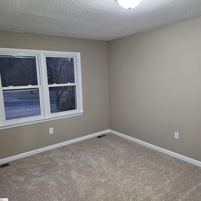 carpeted empty room with a textured ceiling