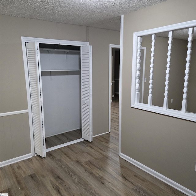 unfurnished bedroom with dark hardwood / wood-style flooring, a closet, and a textured ceiling