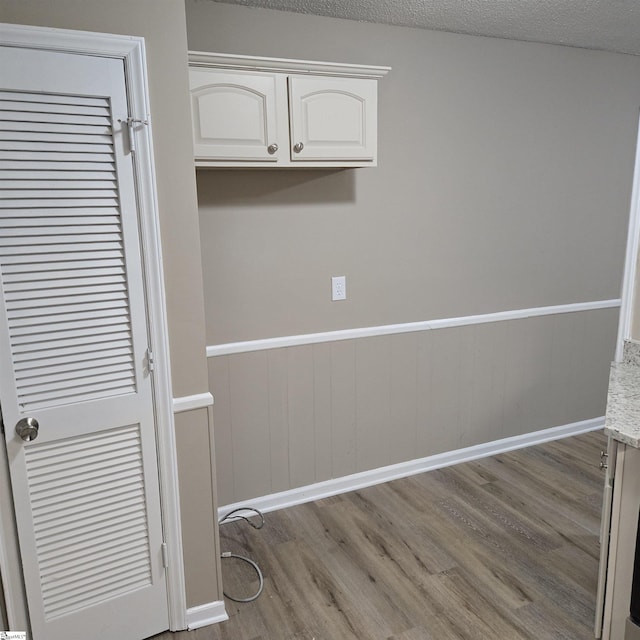 laundry area featuring light hardwood / wood-style flooring and a textured ceiling