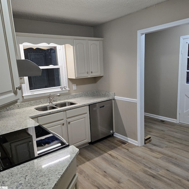 kitchen with white cabinetry, sink, stainless steel dishwasher, light hardwood / wood-style floors, and a textured ceiling