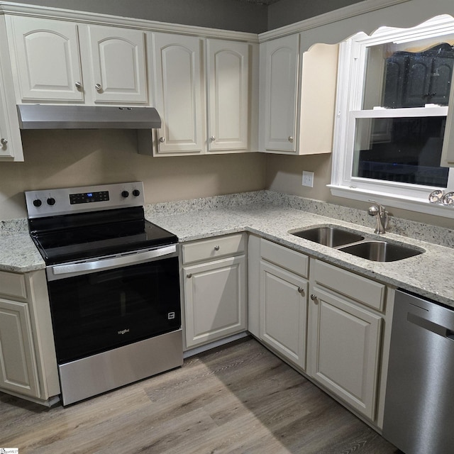 kitchen with sink, white cabinetry, stainless steel appliances, light hardwood / wood-style floors, and light stone countertops