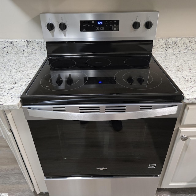 room details featuring light stone countertops, white cabinets, and stainless steel electric range