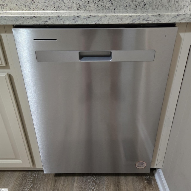 room details with light stone counters, stainless steel dishwasher, and dark wood-type flooring