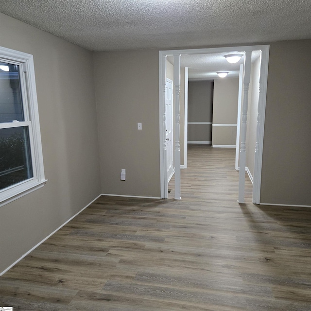 unfurnished room with dark hardwood / wood-style flooring and a textured ceiling