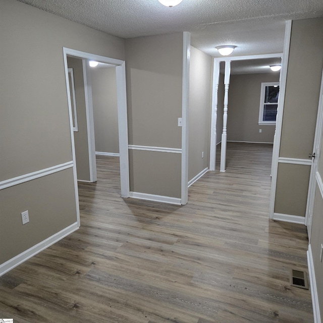 hall featuring a textured ceiling and light hardwood / wood-style floors